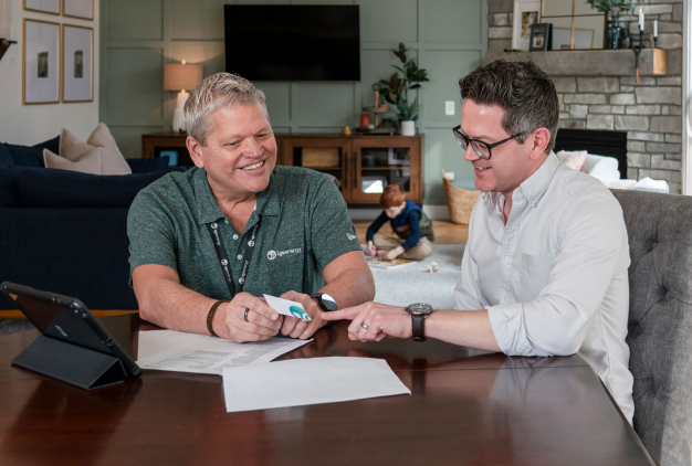 An IGS employee sitting with a homeowner at their dining room table reviewing papers and business cards